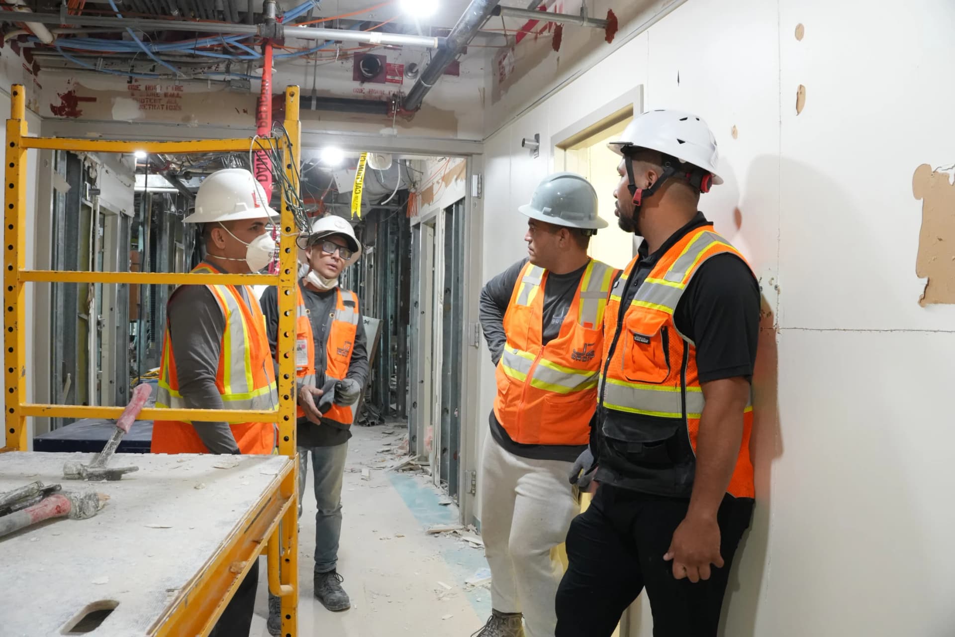 JZ crew discussing work beside a scaffold at the UHealth Tower penthouse